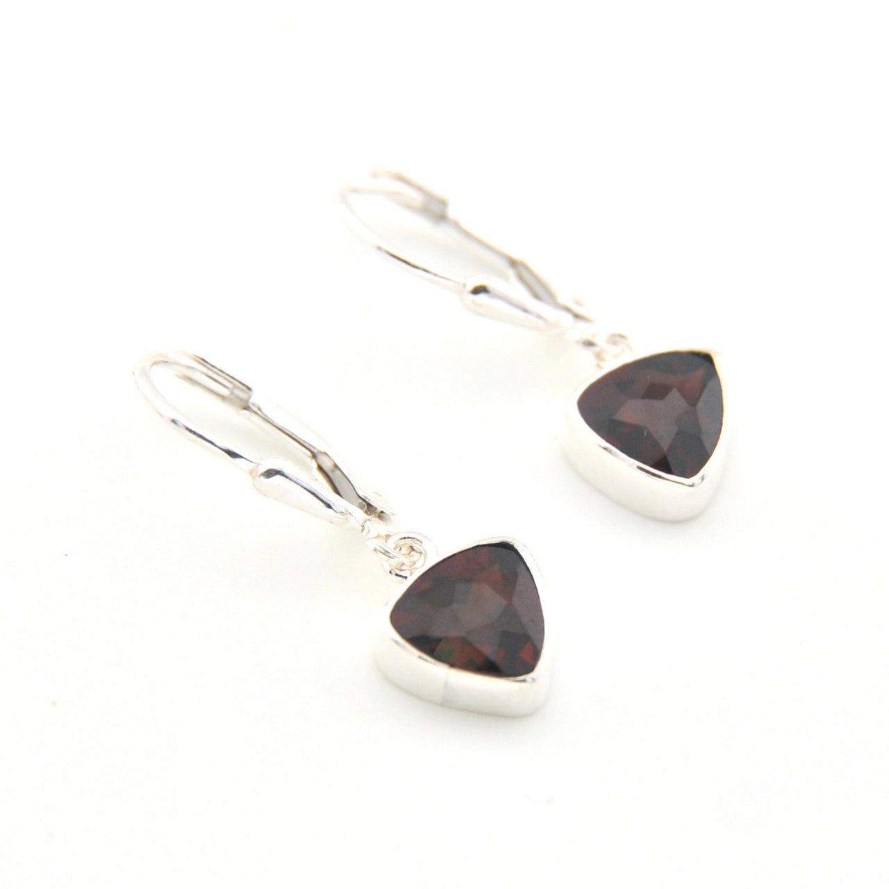 Pair of silver earrings with triangle-shaped garnet stones on a white background