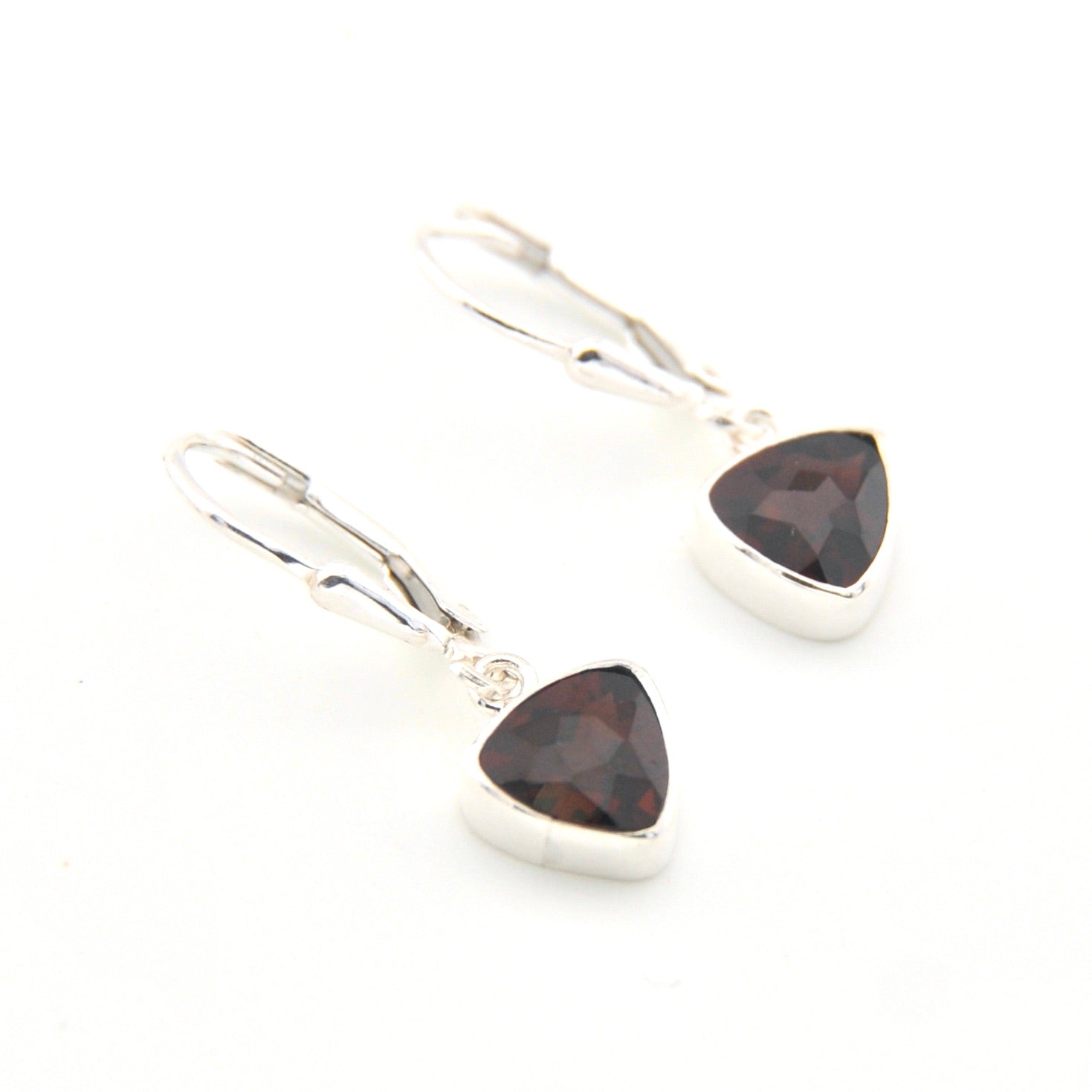 Pair of silver earrings with triangle-shaped garnet stones on a white background