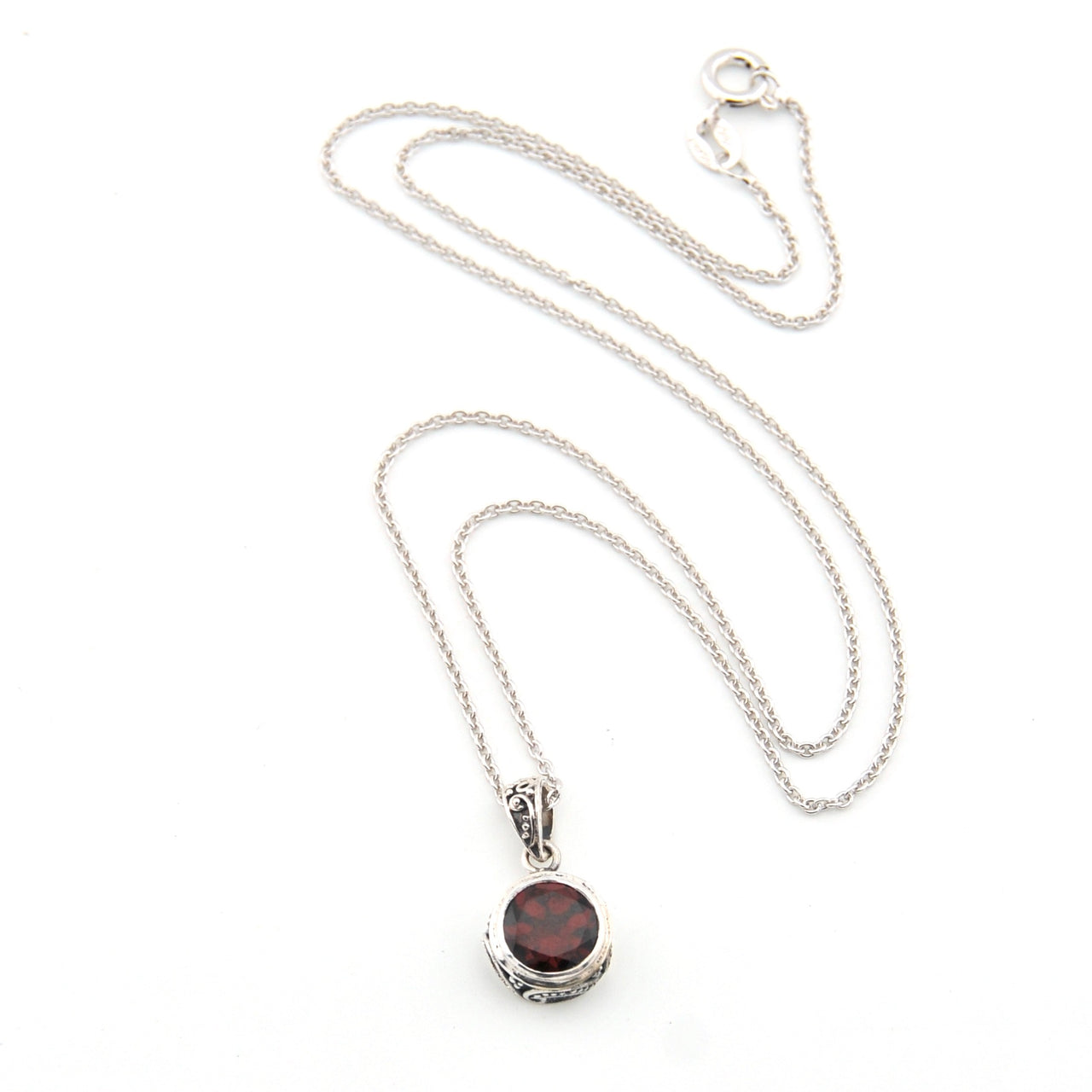 Silver necklace with a pendant featuring a red stone on a white background