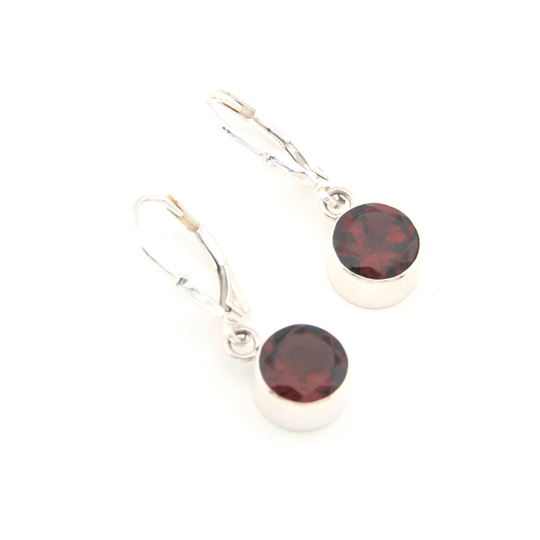 Silver earrings with round red gemstones on a white background
