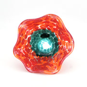 Glass sculpture with orange and red patterns on a white background