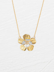 Gold and silver flower-shaped pendant on a chain against a white background