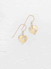 Heart-shaped gold earrings with floral details on a white background