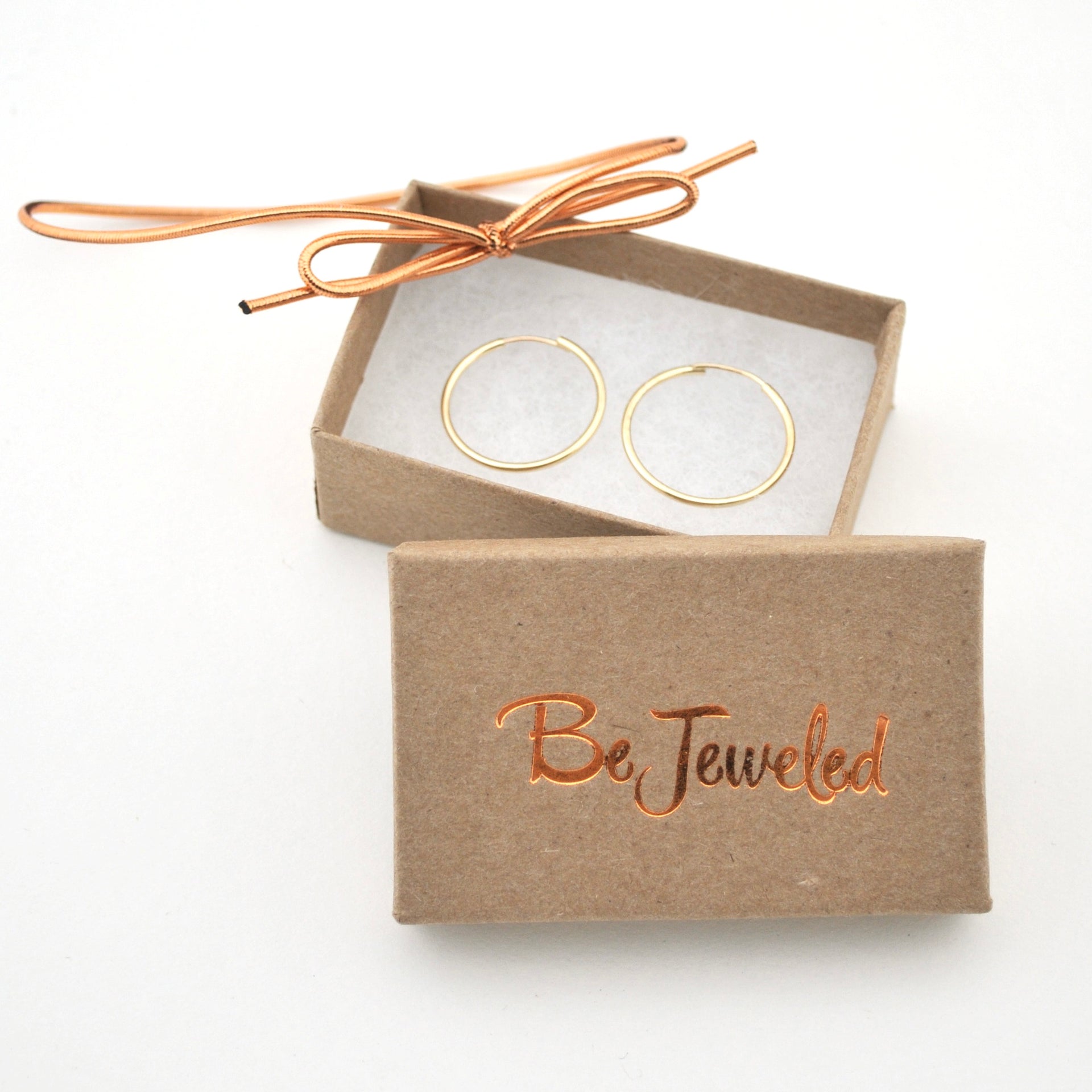 Gold hoop earrings in a 'Be Jeweled' box on a white background
