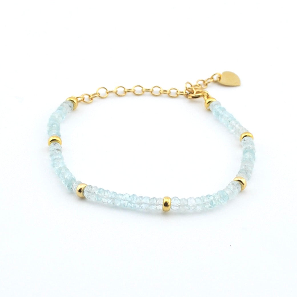 Bracelet with light blue beads and gold accents on a white background