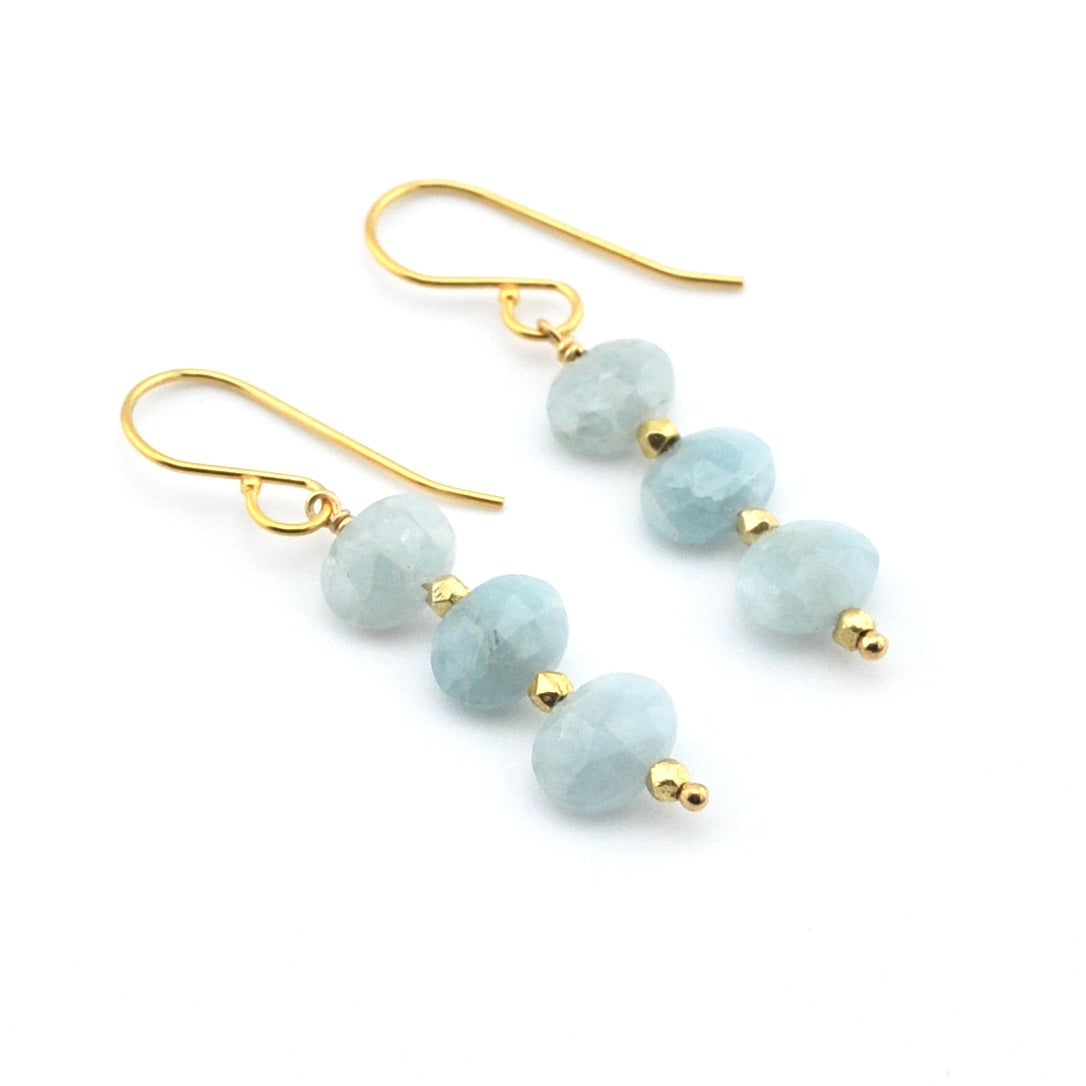 Pair of earrings with light blue beads and gold hooks on a white background