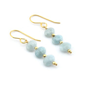 Pair of earrings with light blue beads and gold hooks on a white background