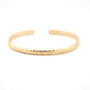 Gold bracelet with intricate design on a white background