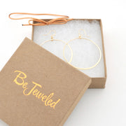 Gold hoop earrings in a 'Be Jeweled' box on a white background