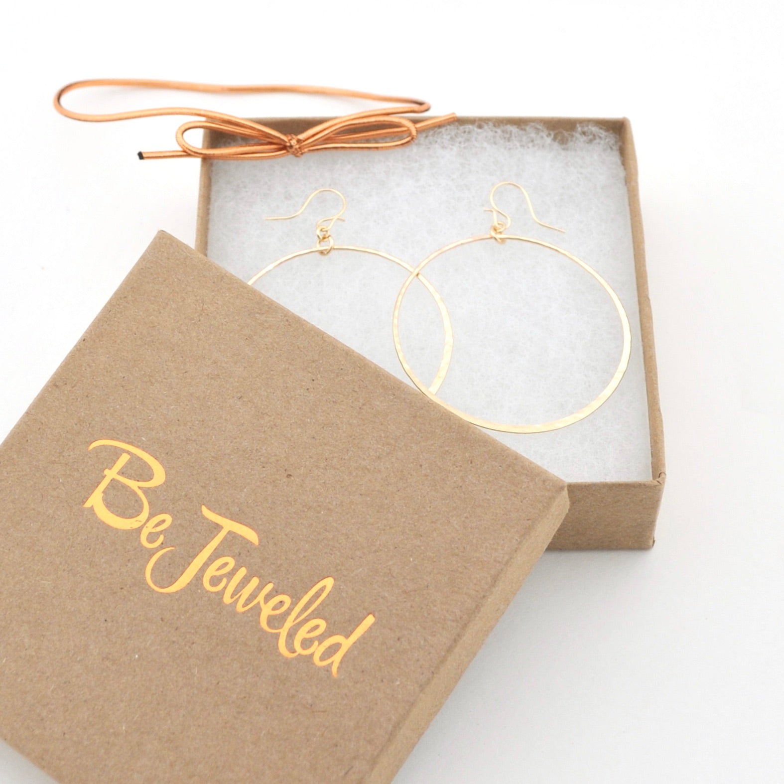 Gold hoop earrings in a 'Be Jeweled' box on a white background
