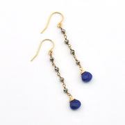 A pair of gold drop earrings with small metallic beads and deep blue oval gemstone pendants, shown on a plain white background.