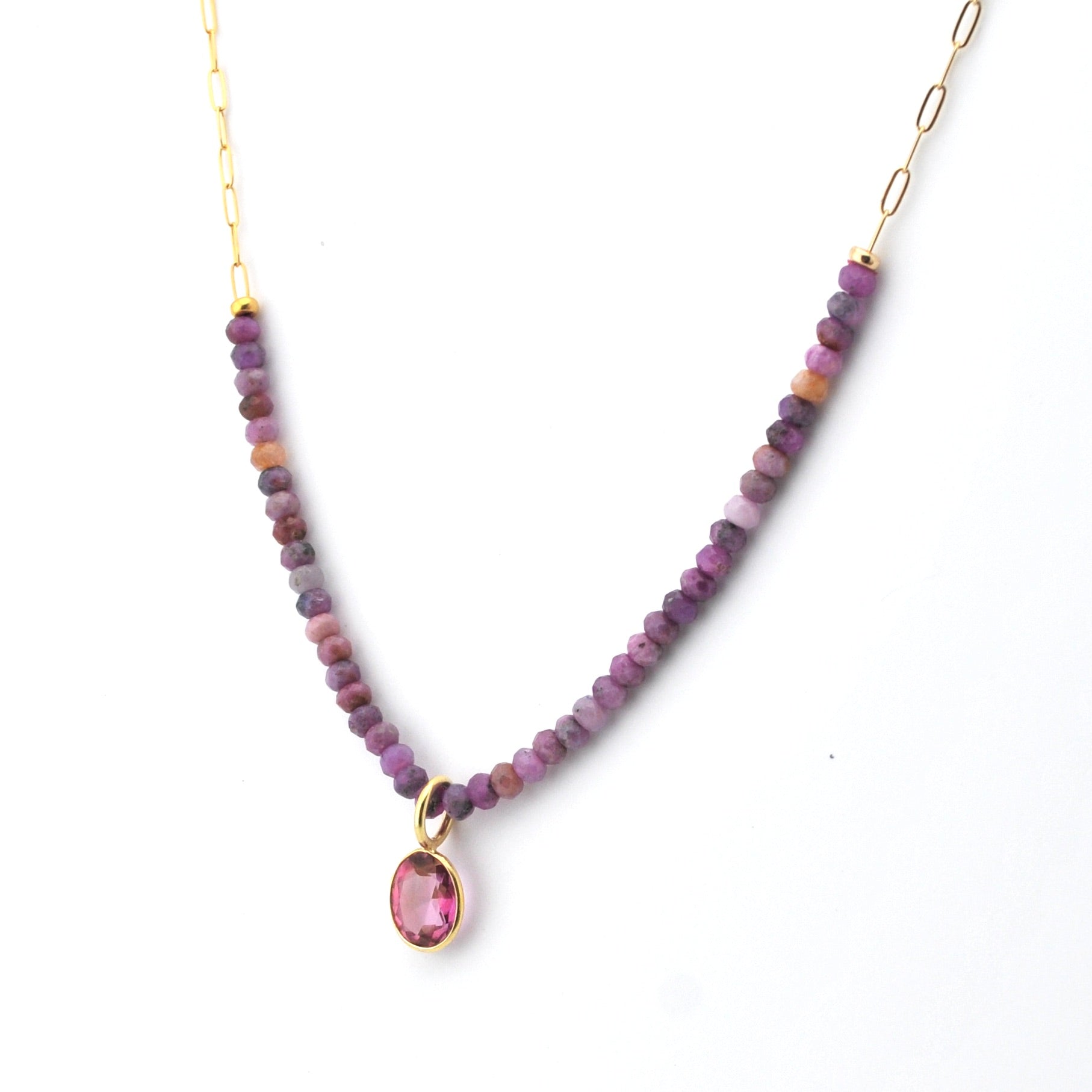 Necklace with purple beads and a pink teardrop pendant on a white background