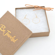 Gold earrings in a 'Be Jeweled' box on a white background