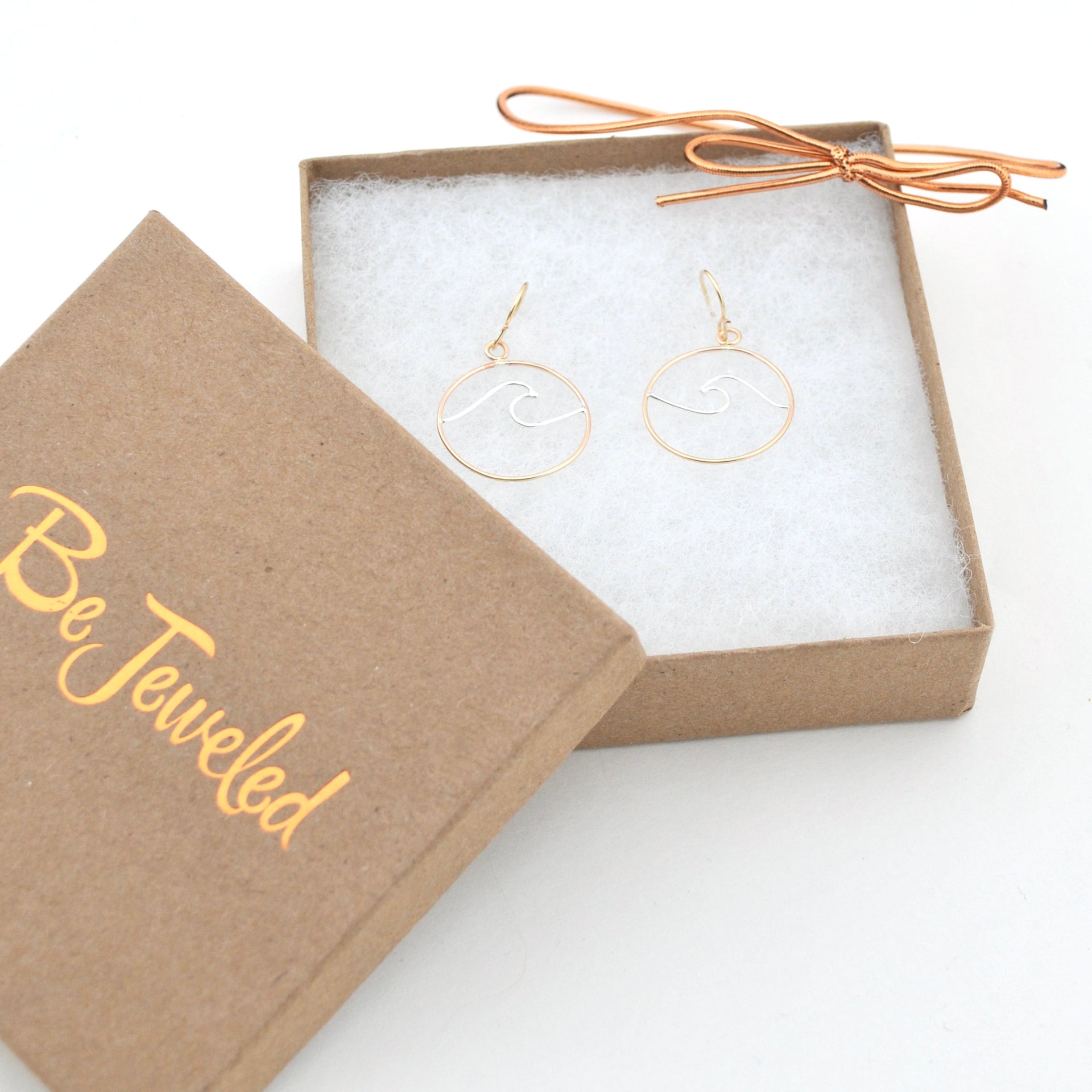 Gold earrings in a 'Be Jeweled' box on a white background