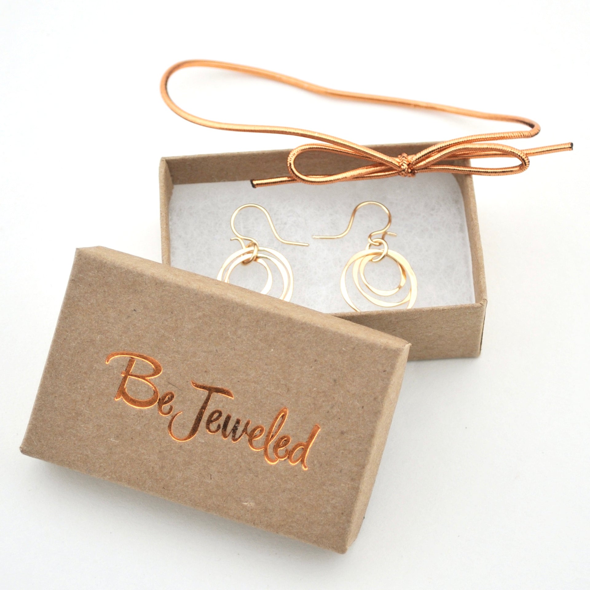 Gold earrings in a 'Be Jeweled' box on a white background