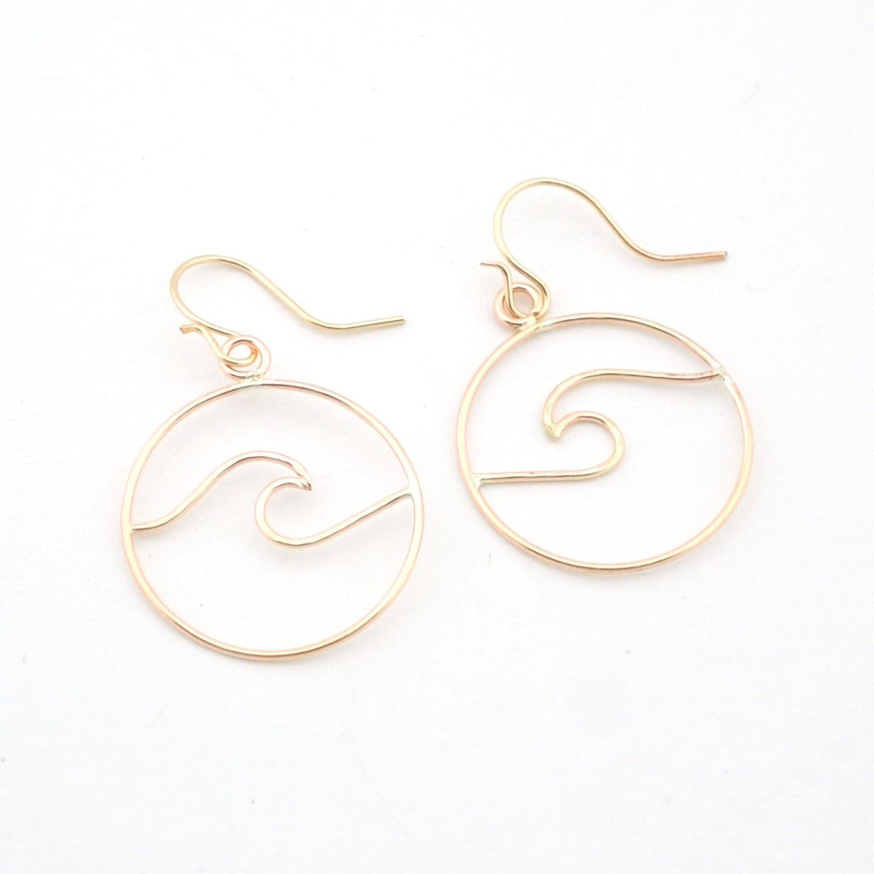 Gold wave-shaped earrings on a white background