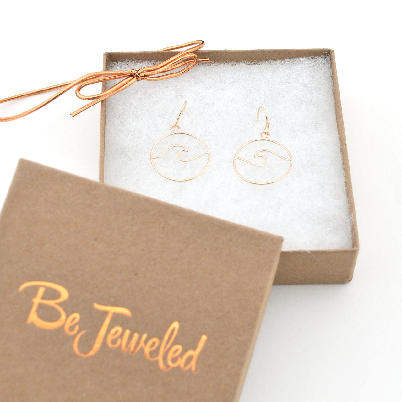 Gold earrings in a 'Be Jeweled' box on a white background