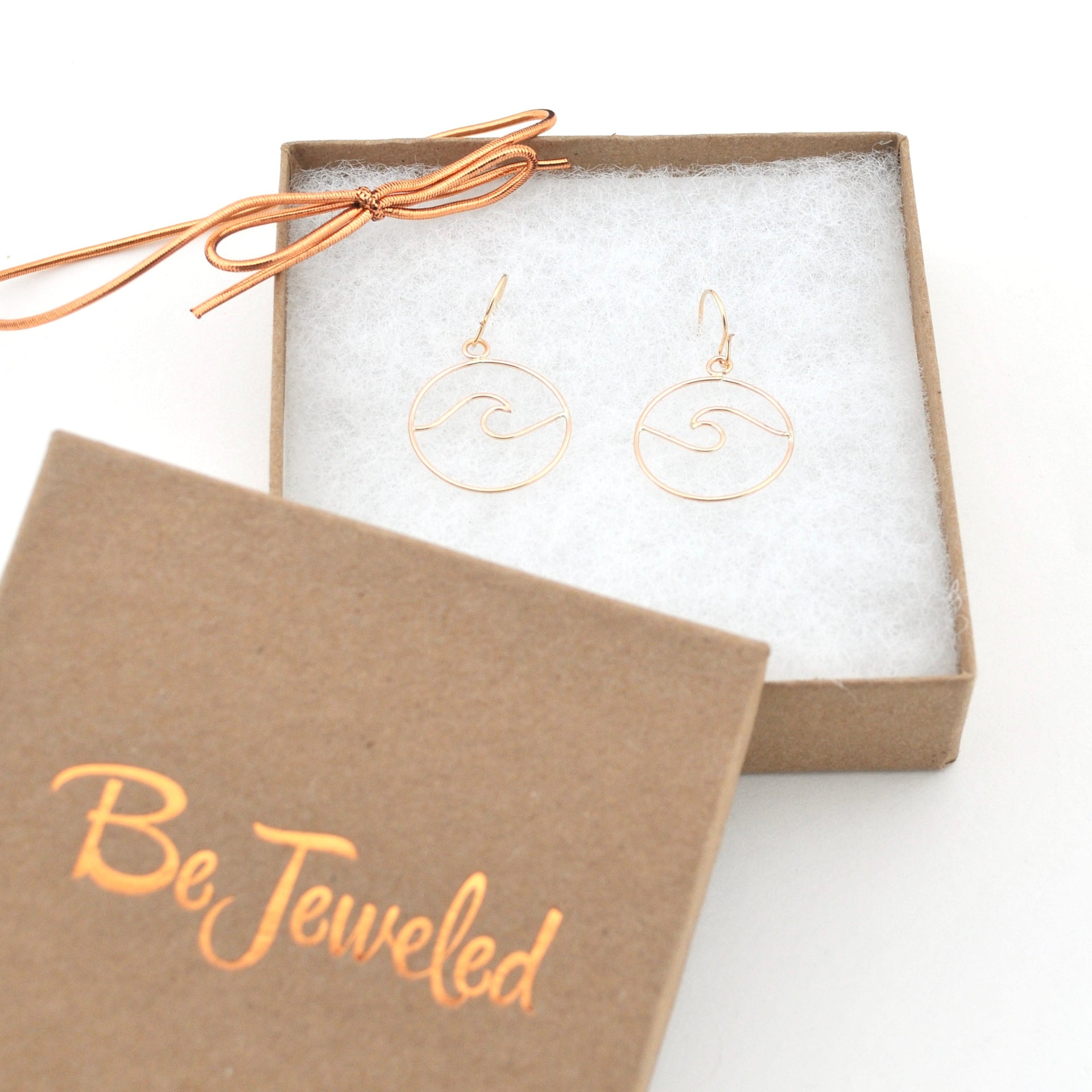 Gold earrings in a 'Be Jeweled' box on a white background