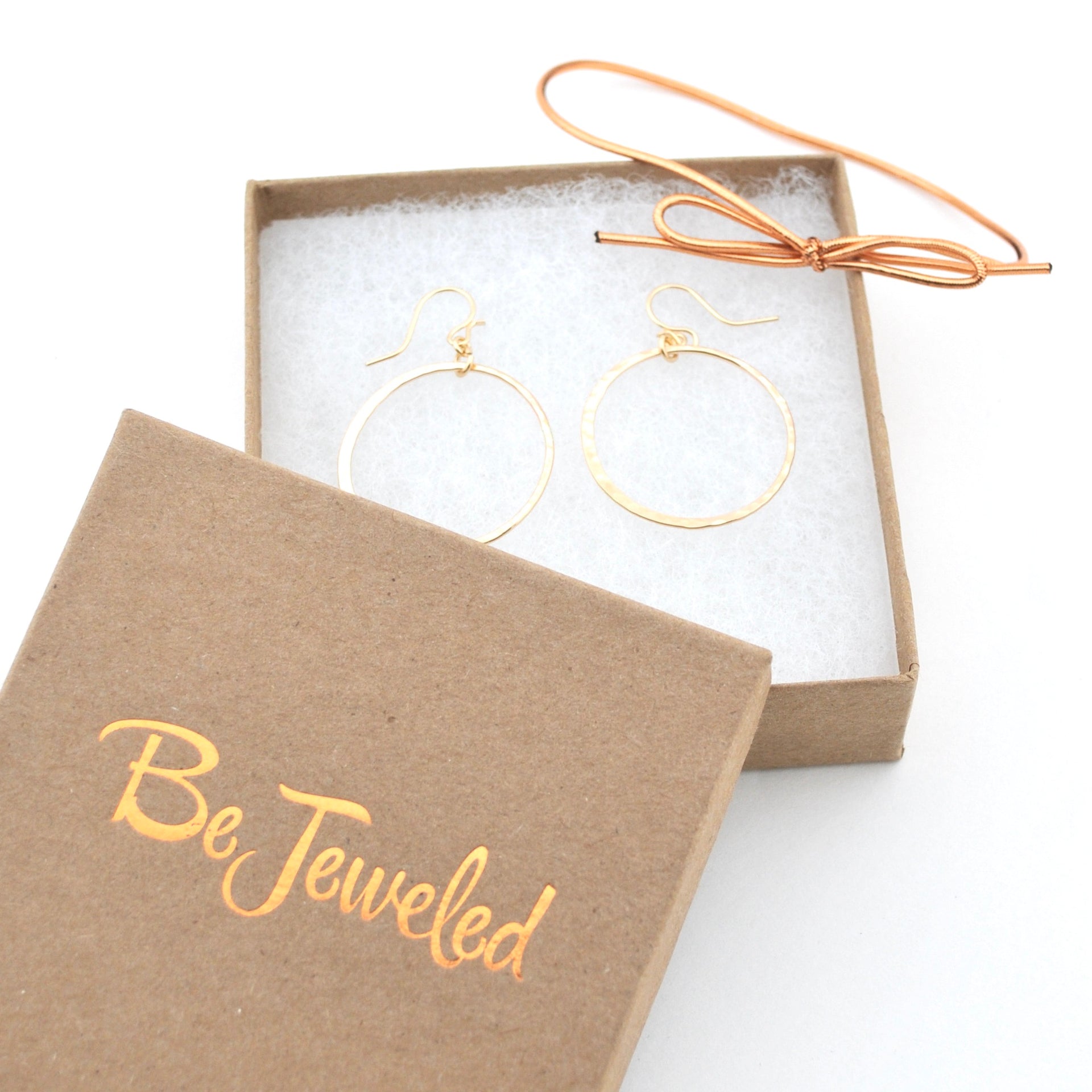 Gold hoop earrings in a 'Be Jeweled' box on a white background