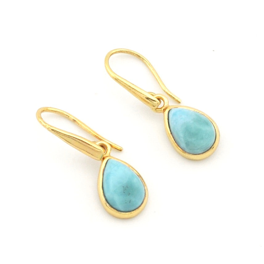A pair of gold drop earrings with teardrop-shaped light blue larimar stones, shown on a plain white background.