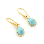 A pair of gold drop earrings with teardrop-shaped light blue larimar stones, shown on a plain white background.