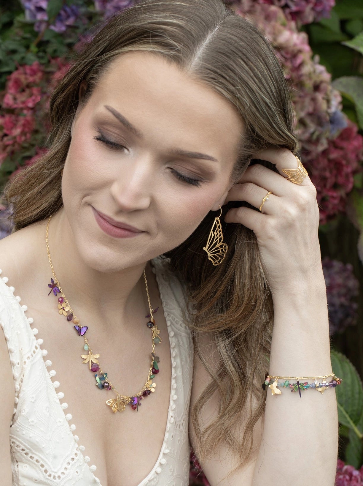 Woman wearing butterfly-themed jewelry with a floral background