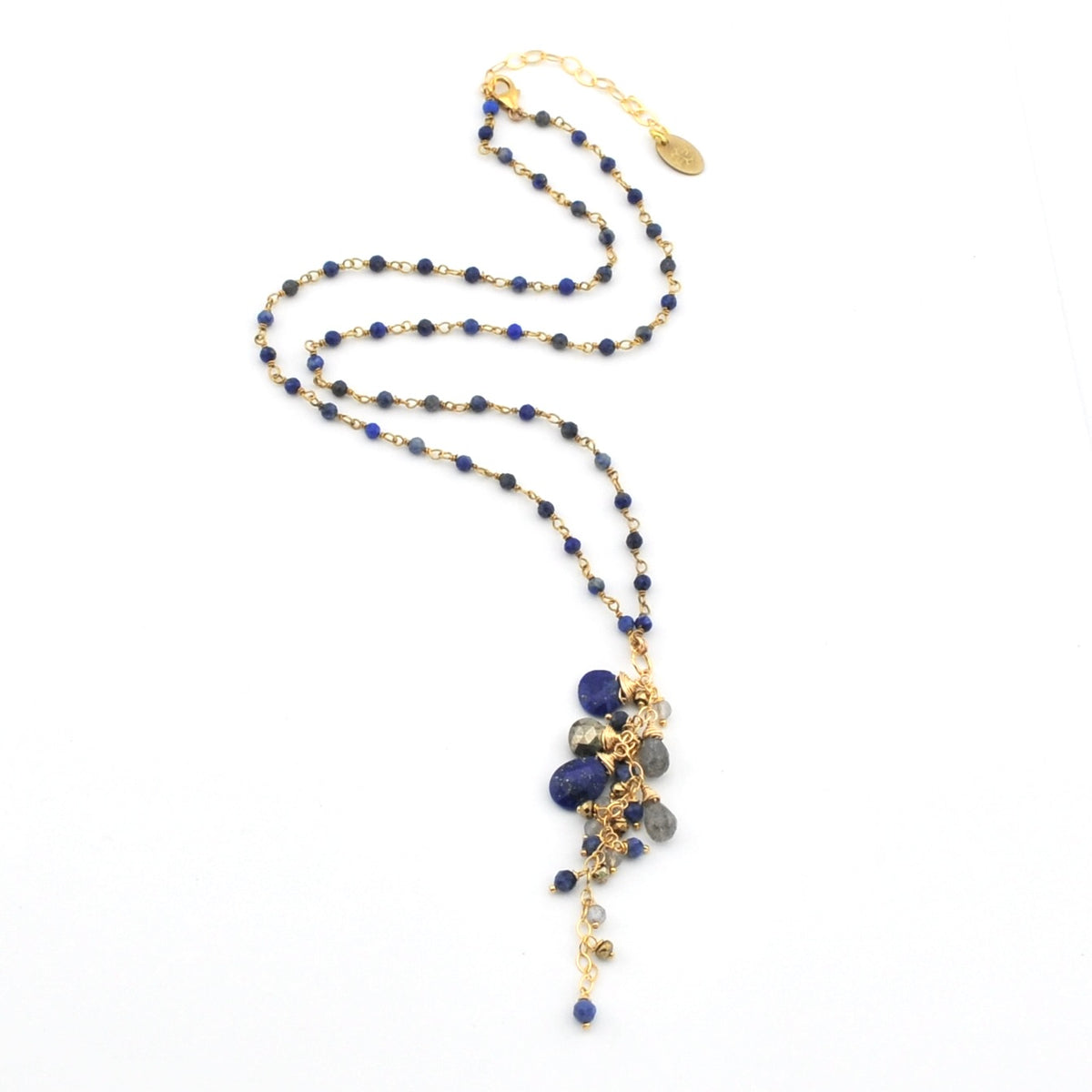 A gold-tone beaded necklace featuring deep blue lapis lazuli and pyriye beads, with a delicate gold chain extender and a small round gold charm, displayed on a clean white background.