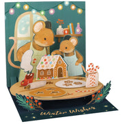 Pop-up card with mice making a gingerbread house, surrounded by festive decorations.