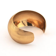 Gold bracelet with a textured design on a white background