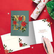 Christmas card with 'Merry' design on a red surface with wrapping paper and a pen.