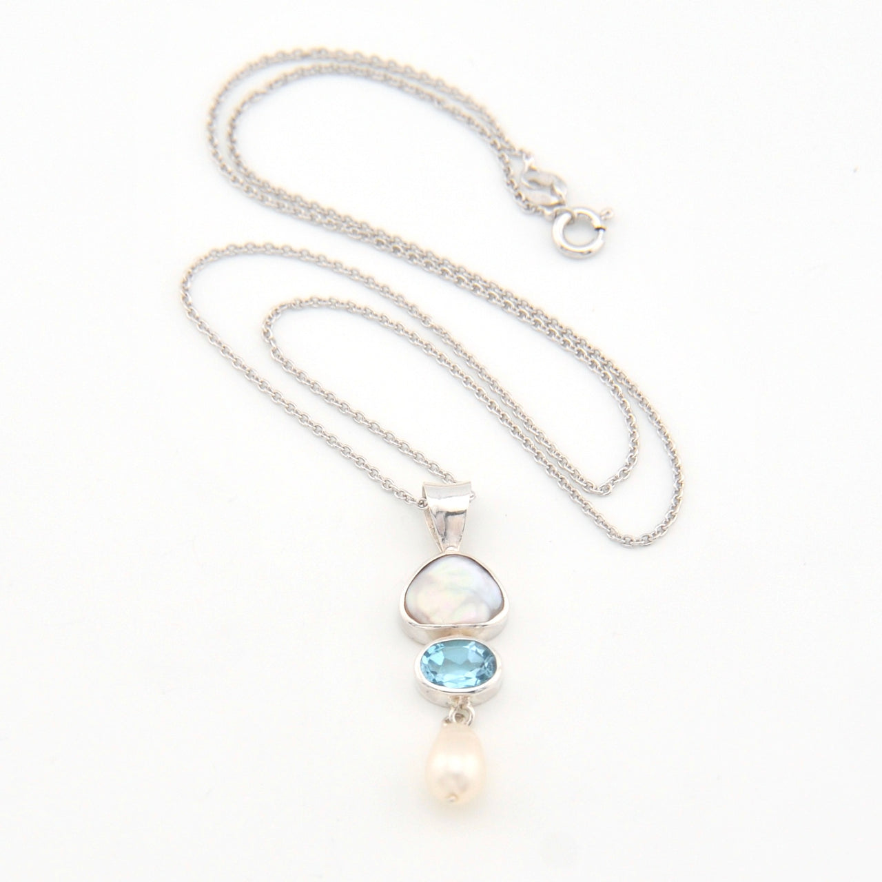 Silver necklace with a pendant featuring a blue gemstone and pearl on a white background