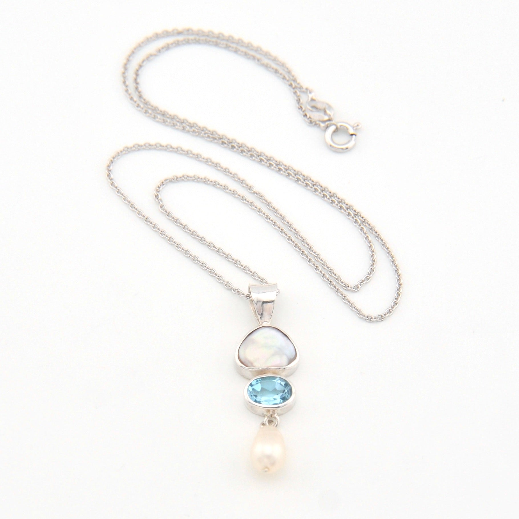 Silver necklace with a pendant featuring a blue gemstone and pearl on a white background