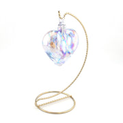 Heart-shaped glass ornament with gold stand on a white background