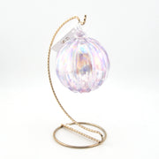 Iridescent glass ornament with a gold stand on a white background