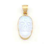 Gold pendant with a face design on a white background