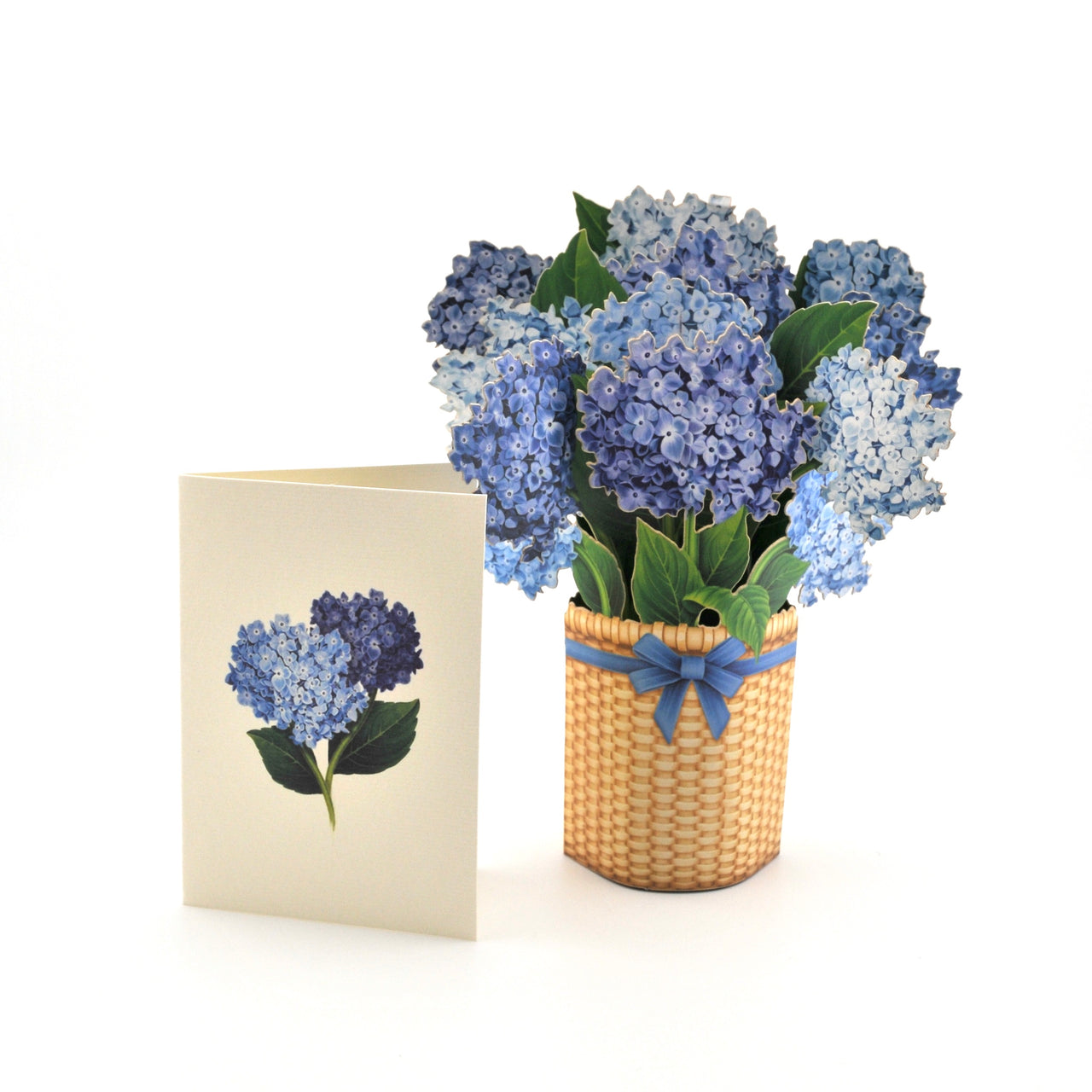 Bouquet of blue flowers in a woven basket with a matching card on a white background