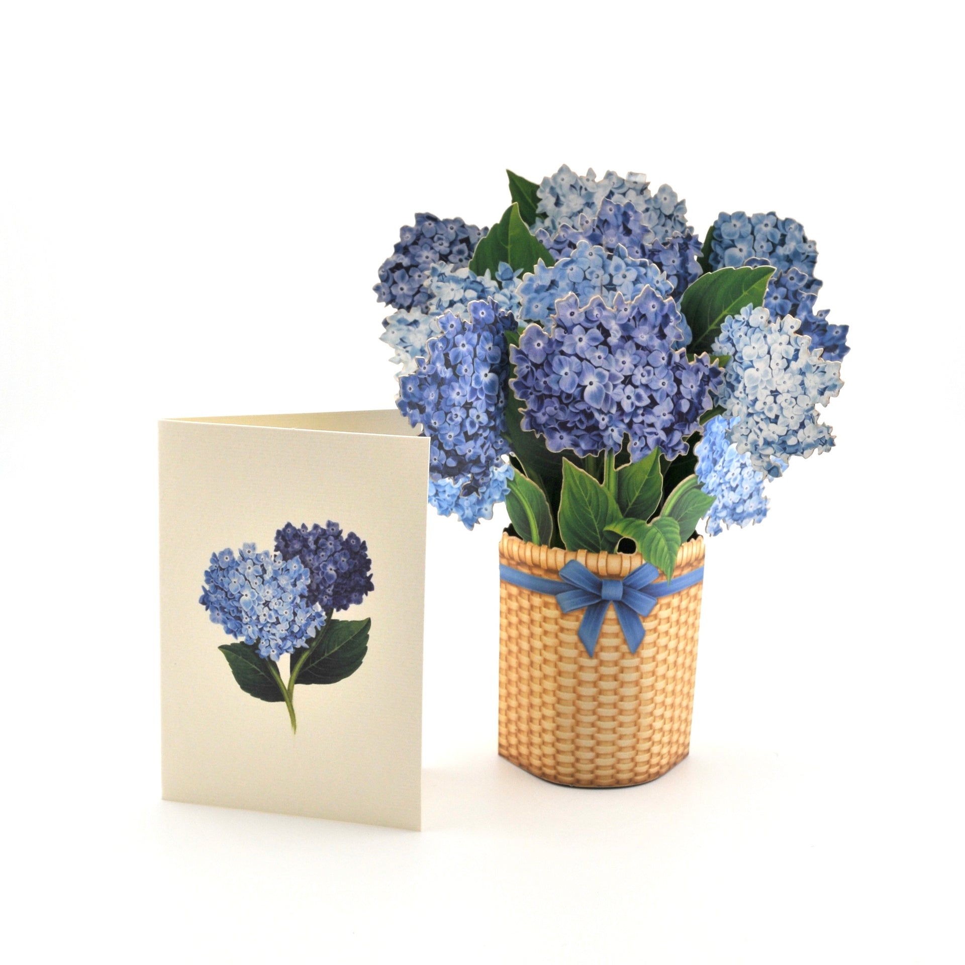 Bouquet of blue flowers in a woven basket with a matching card on a white background