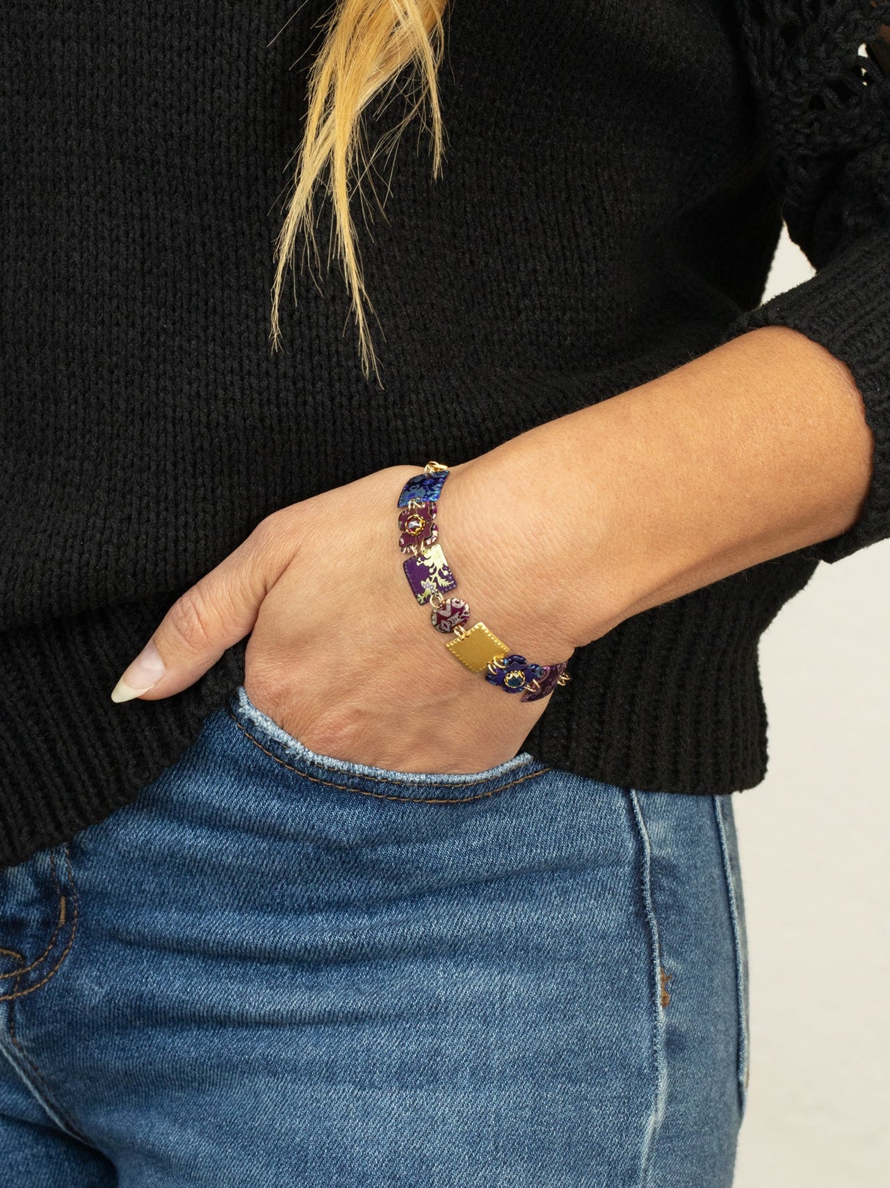 Person wearing a colorful beaded bracelet on a plain background
