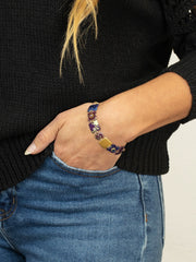 Person wearing a colorful beaded bracelet on a plain background