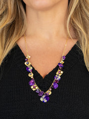 Necklace with purple and gold beads worn by a person against a black background