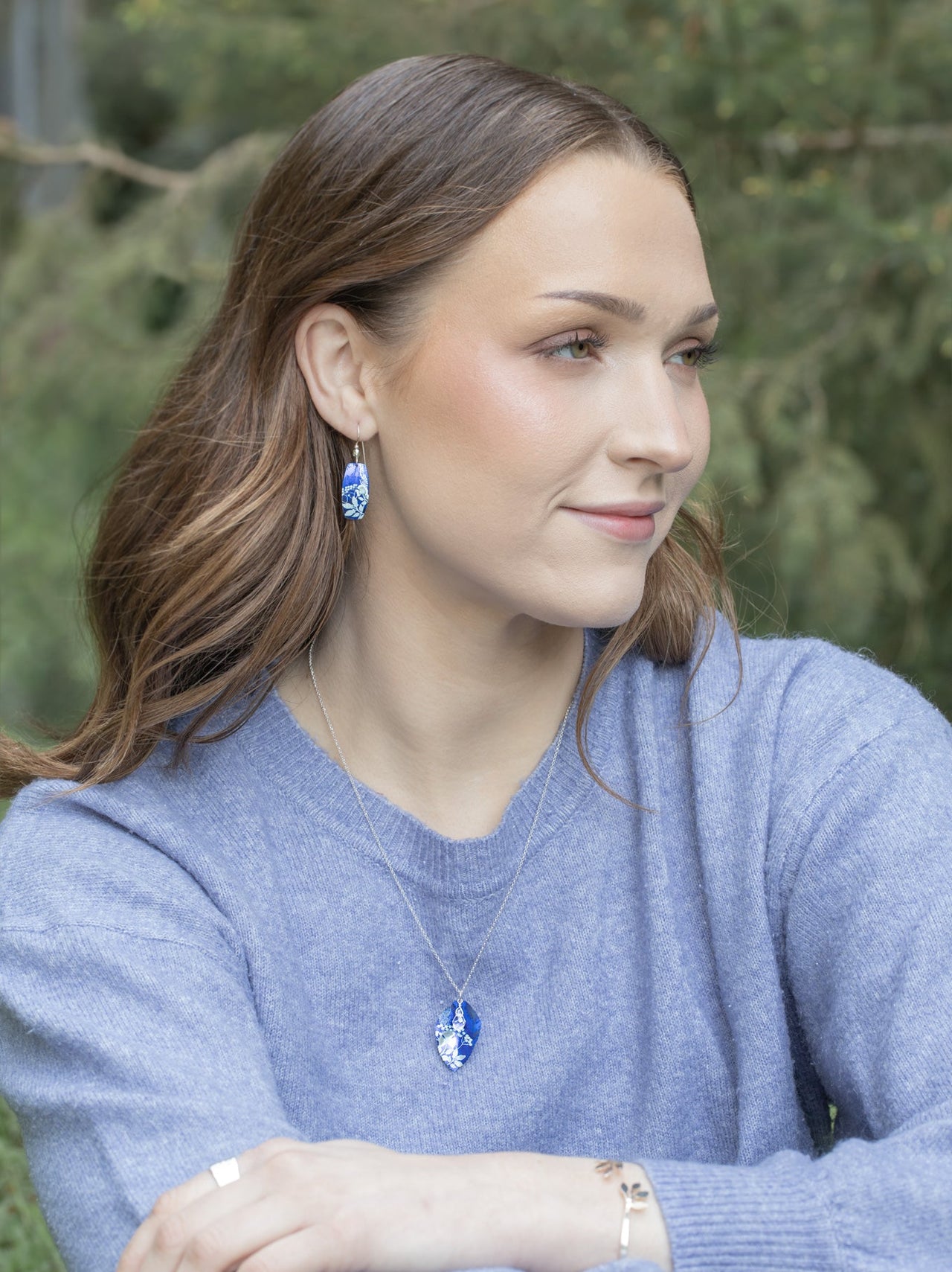 Woman wearing a blue sweater with a blurred green background