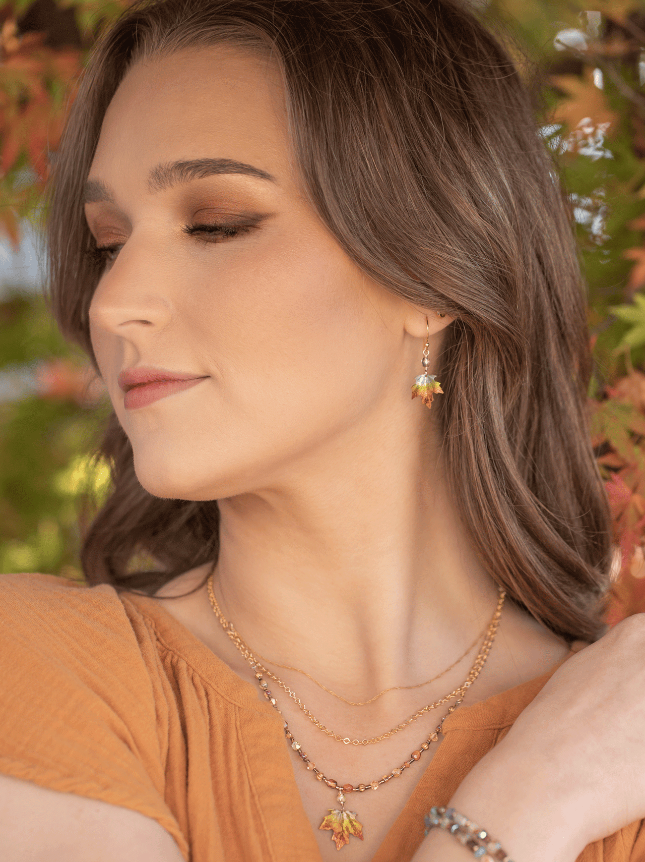 Woman wearing a necklace and earrings with a blurred natural background