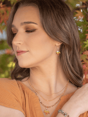 Woman wearing a necklace and earrings with a blurred natural background