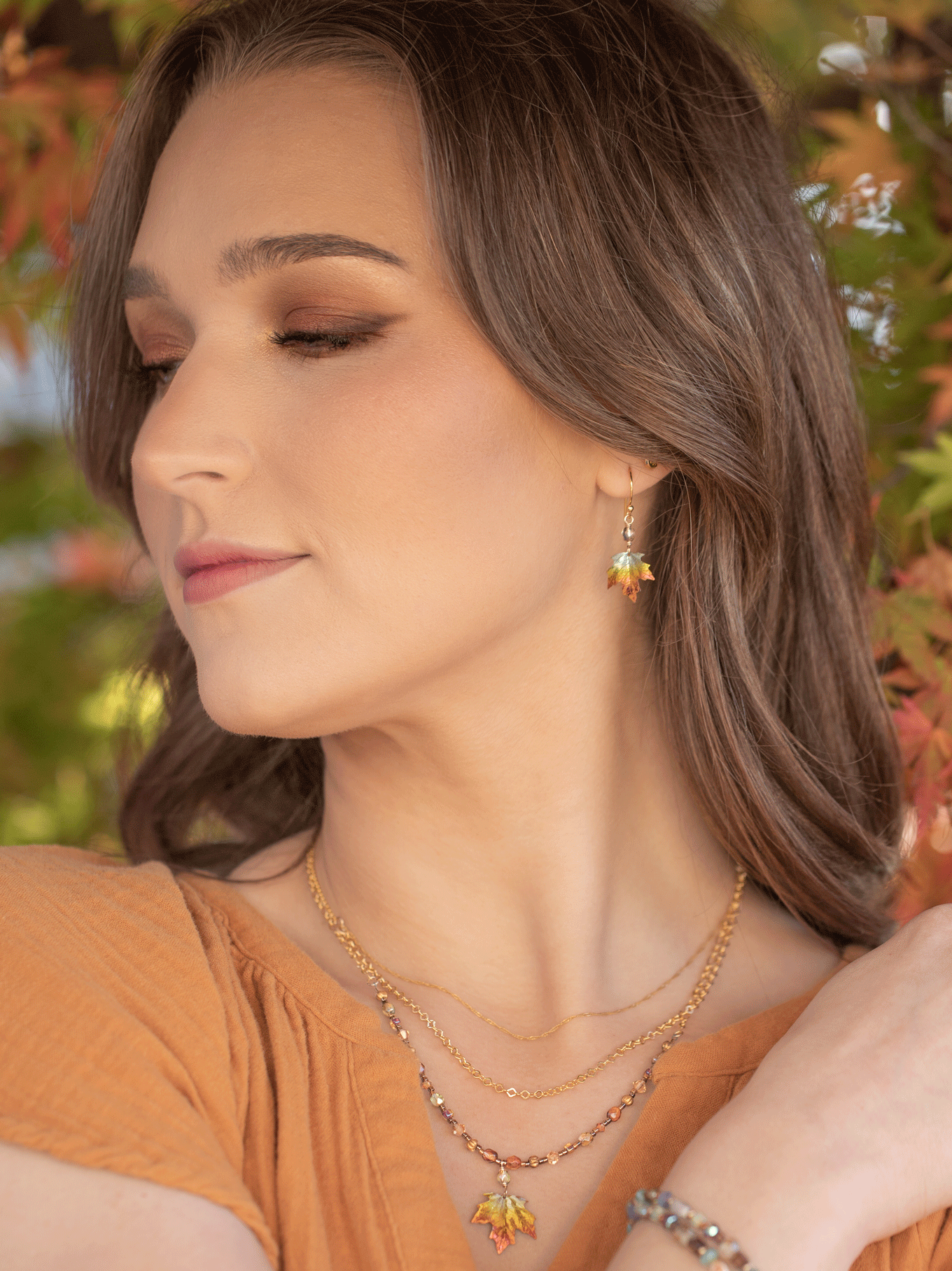 Woman wearing a necklace and earrings with a blurred natural background