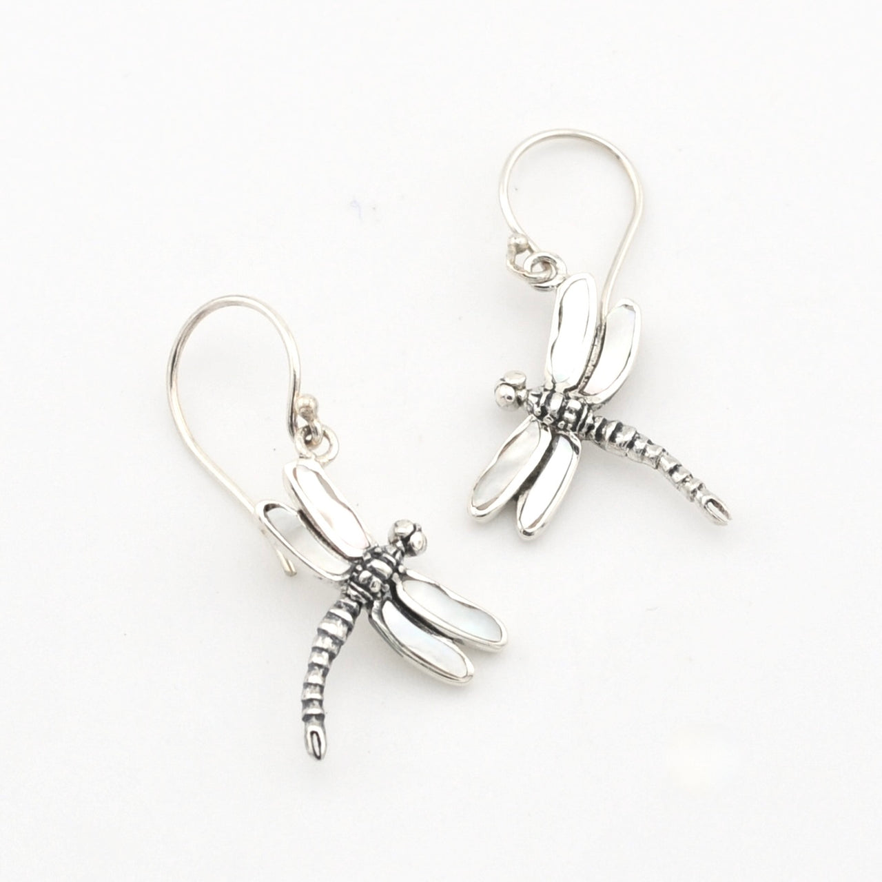 A pair of silver dragonfly drop earrings with textured wings and hooks, displayed on a clean white background.