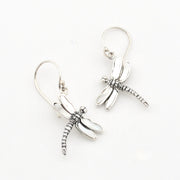 A pair of silver dragonfly drop earrings with textured wings and hooks, displayed on a clean white background.