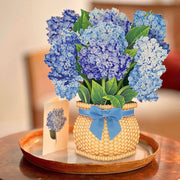 Bouquet of blue flowers in a woven basket with a blue ribbon on a wooden surface.