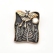 Decorative brooch with luna moth design on a white background