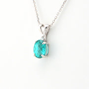Silver necklace with a green gemstone pendant on a white background