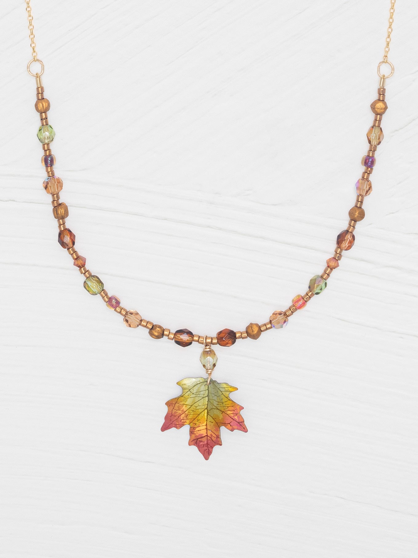 Necklace with leaf pendant and multicolored beads on a white background
